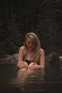 woman in body of water near rock thumbnail