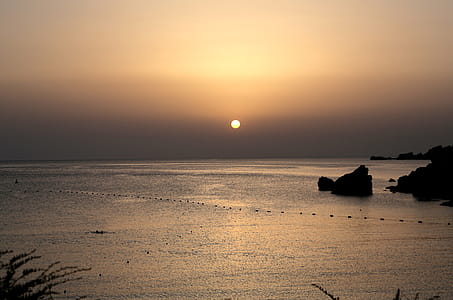 A sunset view of horizon with waves and rocks thumbnail