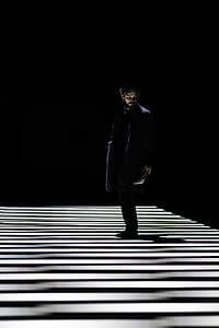 man standing on stripe shadowed floor thumbnail