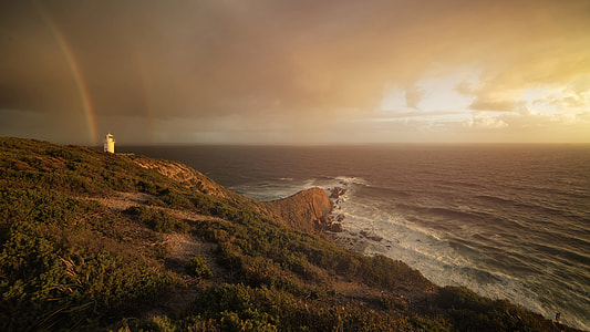 white lighthouse near ocean during golden hour thumbnail
