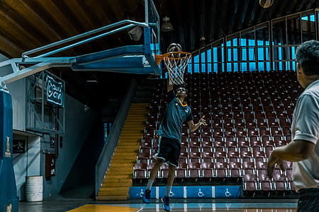 Man in Blue Shirt Trying to Dunk in Basketball Ring thumbnail