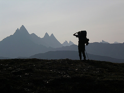 silhouette of person carrying hiking backpack standing near mountain thumbnail