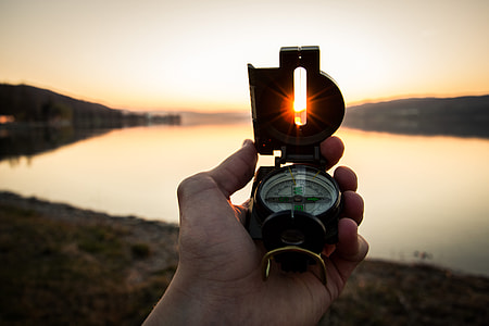 person holding brass-colored military compass thumbnail