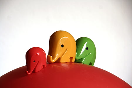 three green, yellow, and red elephant figurine on red round surface thumbnail