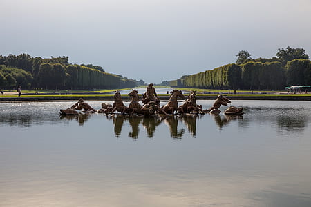 statue of team of brown horses on water near trees at daytime thumbnail