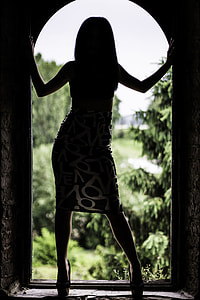 silhouette photo of woman on arch framed door near trees thumbnail