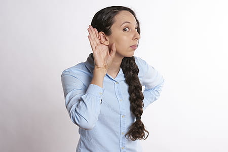woman putting her right hand near her ear while listening thumbnail