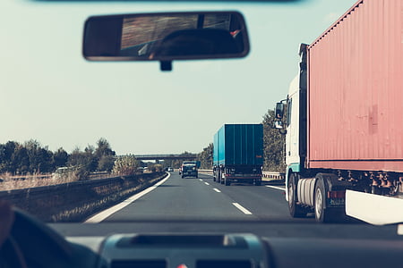 two freight trucks passing black van thumbnail