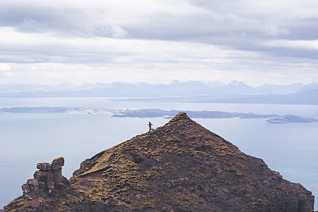 person standing atop of a mountain during day time thumbnail