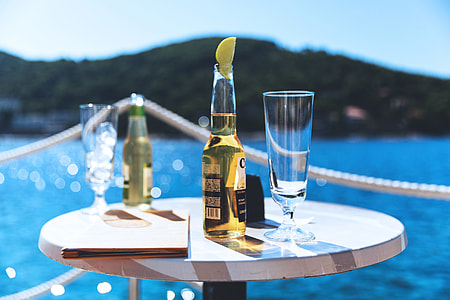 Beer and lager bottles and glasses on a table on the coast in summer time thumbnail