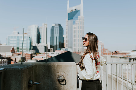 woman standing on guard rail in front of buildings thumbnail