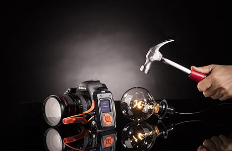 person holding hammer in front of Edison bulb beside camera thumbnail