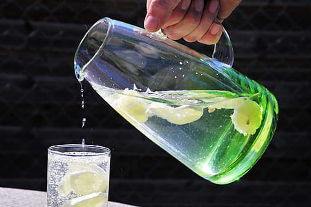 person pouring clear glass pitcher on glass detox water thumbnail
