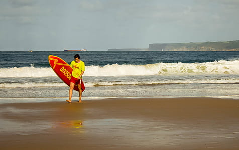 man carrying red and yellow surfboard thumbnail