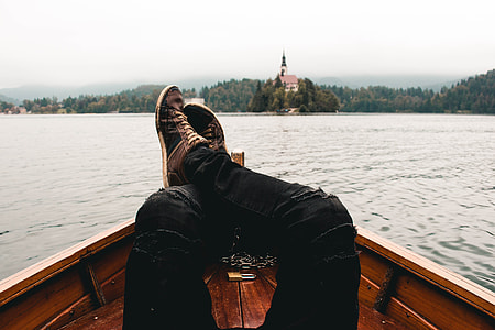 person lying on boat legs crossed on rail on body of water thumbnail