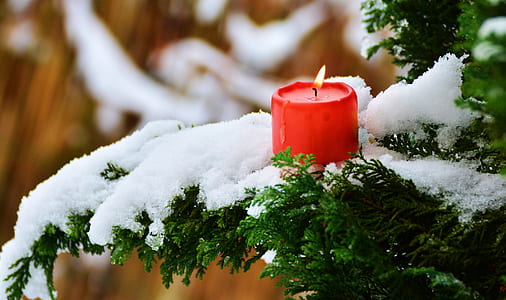 red pillar candle on white snow thumbnail