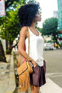 woman in white tank top with brown leather shoulder bag standing on street during daytime thumbnail