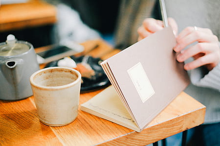person holding book white sitting in front of table thumbnail
