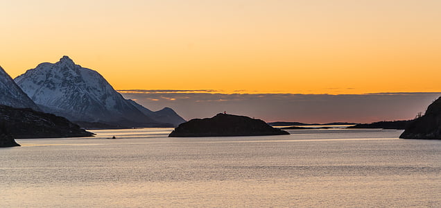 silhouette of rock formation surrounded by body of water thumbnail