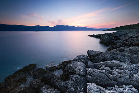 body of water near mountain during daytime thumbnail