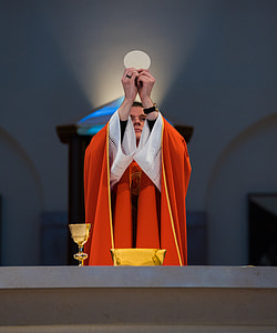 photography of priest holding flat bread thumbnail