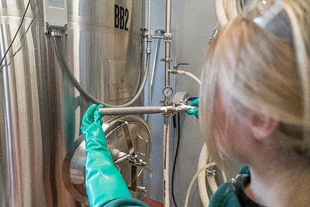 Person Wearing Gloves While Fixing Distillation Tank thumbnail