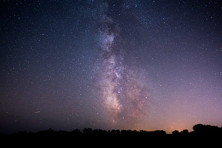 photo of silhouette of trees under view of cosmos on sky thumbnail