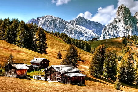 brown wooden house near mountains during daytime thumbnail