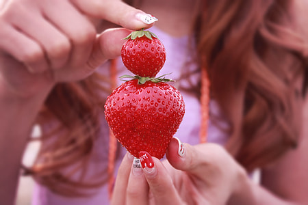 woman holding two strawberry fruits thumbnail