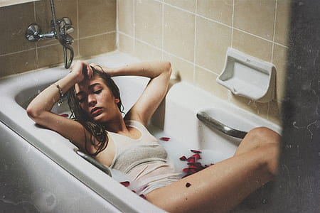 photo of woman lying on white ceramic bath tub thumbnail