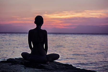 silhouette of a woman sitting on a coastal rock thumbnail