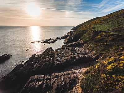 cliff beside beach under sun rays thumbnail