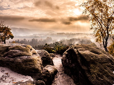 rocky hill and forest under cloudy sky during daytime thumbnail