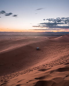 white off-road car driving on sand dunes thumbnail