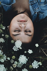 woman lying down beside white flowers closed eyes thumbnail