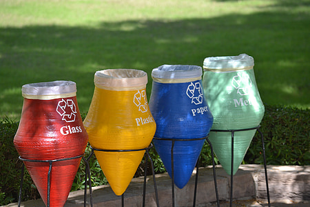 four assorted-color garbage pots near green grass field thumbnail