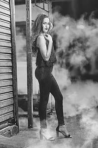 grayscale photo of woman standing near shutter door thumbnail