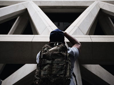 men in white shirt with bag standing in front of a building thumbnail