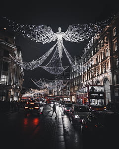lighted angel string lights above road mounted on large buildings at night thumbnail