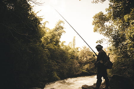 photograph of person holding fishing rod beside river thumbnail