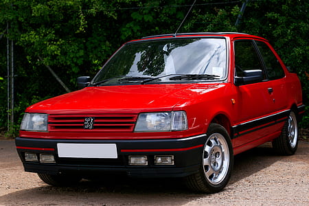 parked red Peugeot coupe near green leaf trees thumbnail