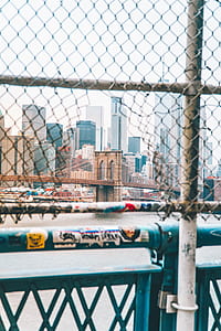 tilt-shift lens photography of Brooklyn Bridge through wire fence thumbnail