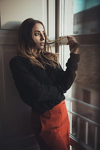 woman leaning on wooden door looking outside house thumbnail