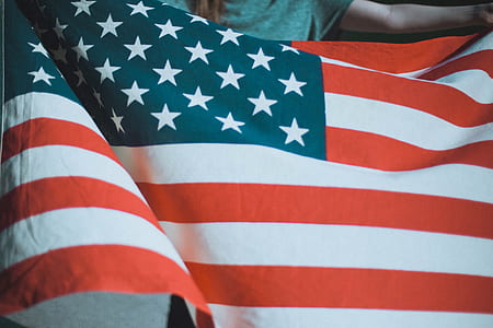 person in gray top holding flag of USA thumbnail