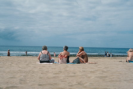 three people sitting on beach sand thumbnail