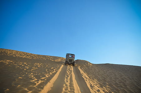 gray vehicle travelling in dessert at daytime thumbnail