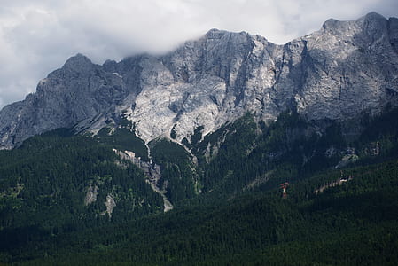 green trees and mountain under cloudy sky thumbnail