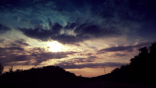 silhouette of mountain under cloudy sky during golden hour thumbnail