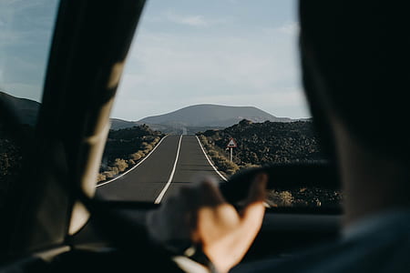 selective focus photography of man driving on empty road thumbnail