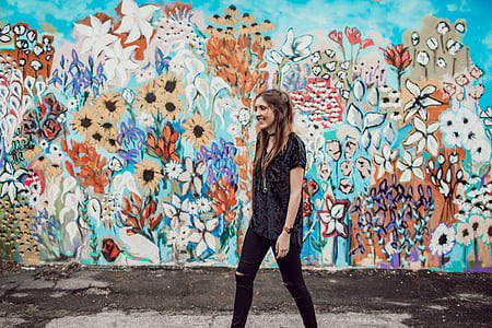 woman standing in front of concrete wall with flower painting thumbnail